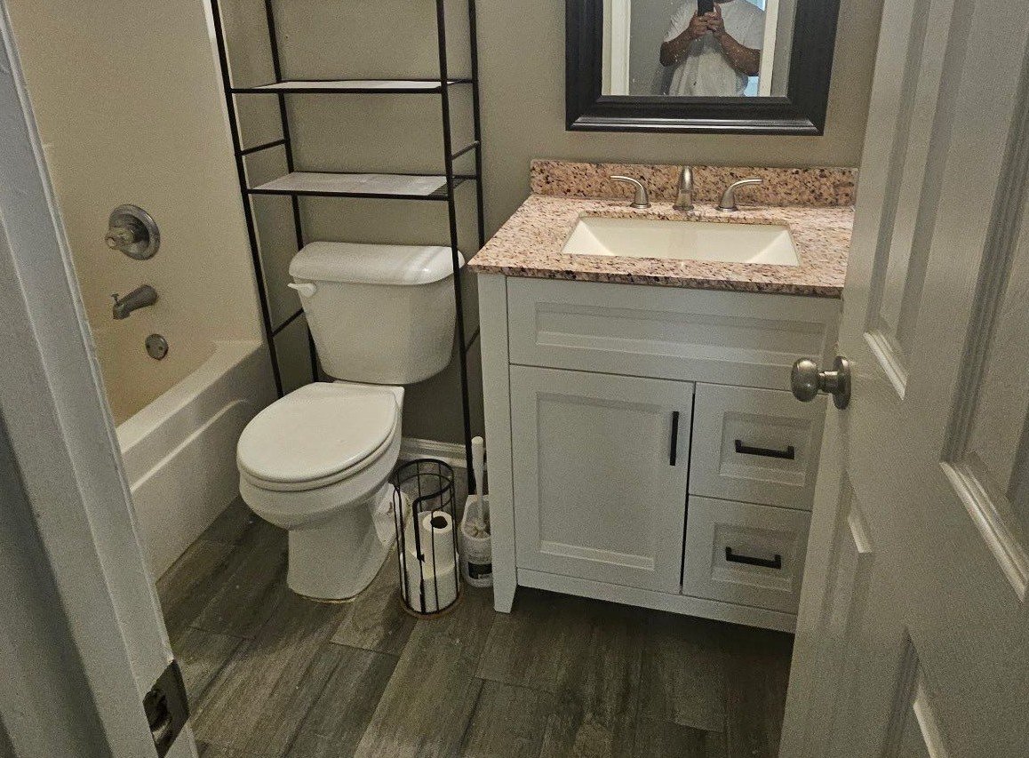 Fully restored upstairs bathroom in Lithonia, GA with new shower, vanity, toilet, and LVP flooring.