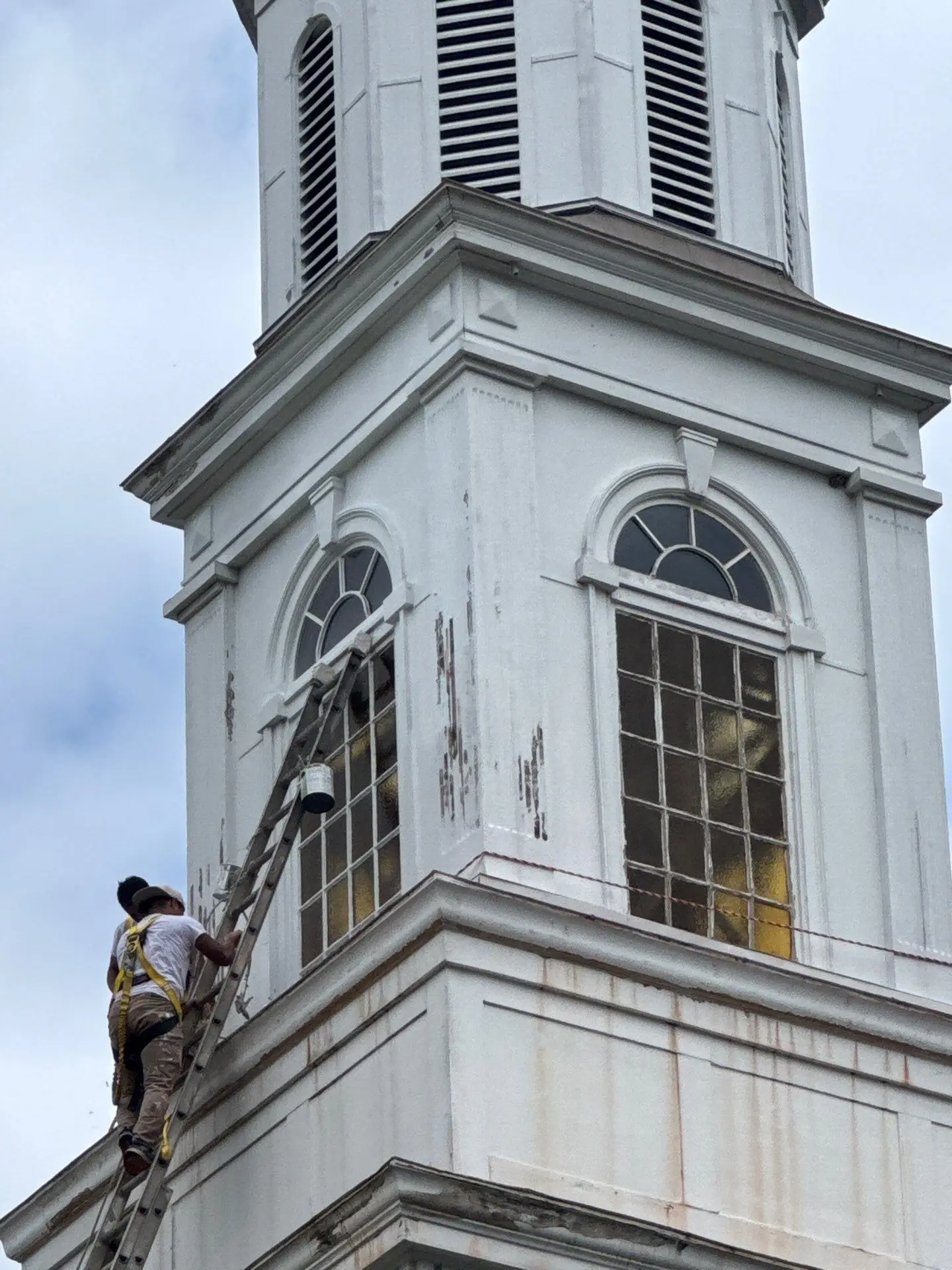 Exterior of Berean Seventh-Day Adventist Church sanctuary showing peeling paint, water-stained wood trim, and structural deterioration on the eaves.