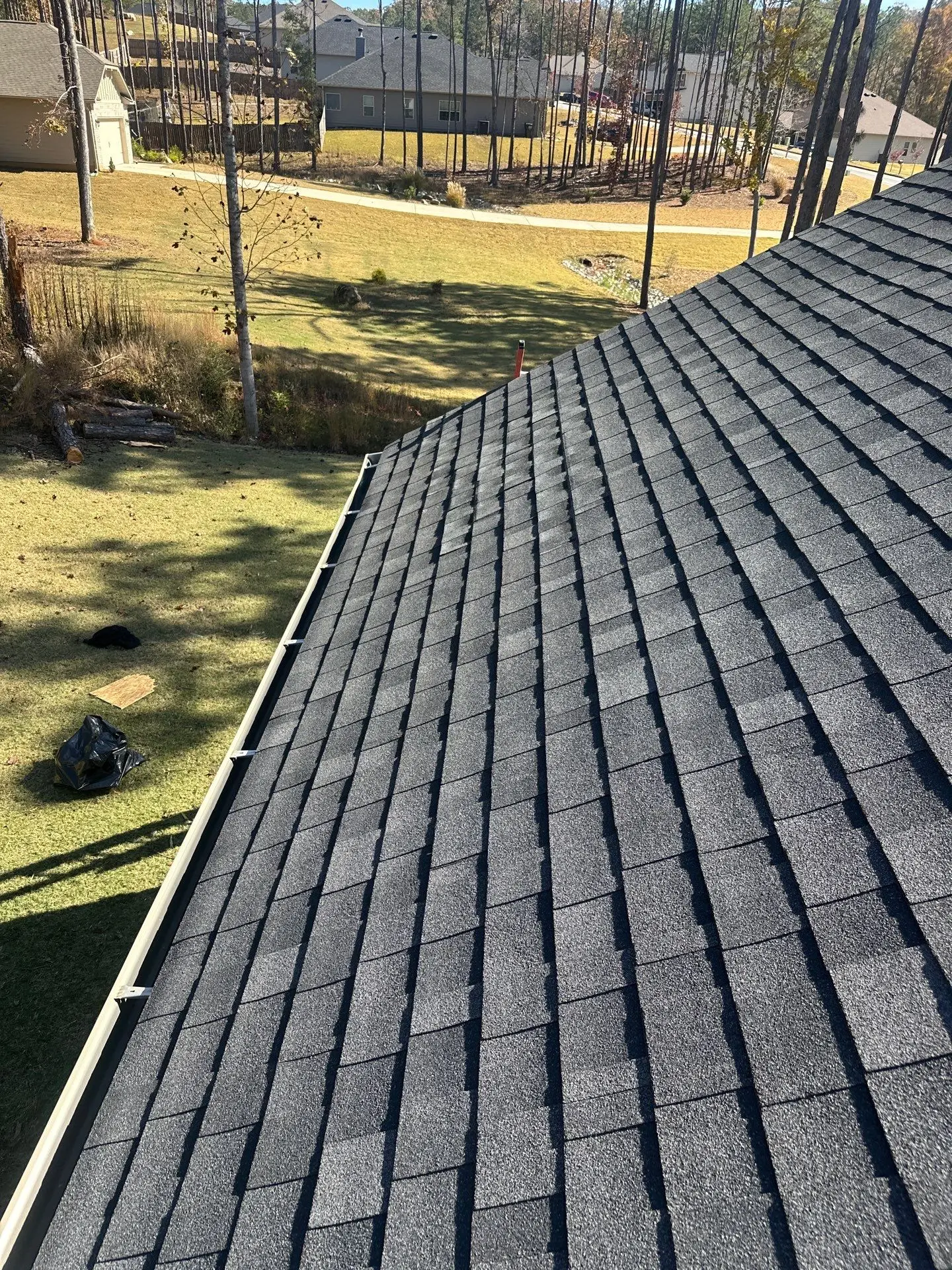 Repaired section of roof with new matching charcoal architectural shingles and straightened gutter system.