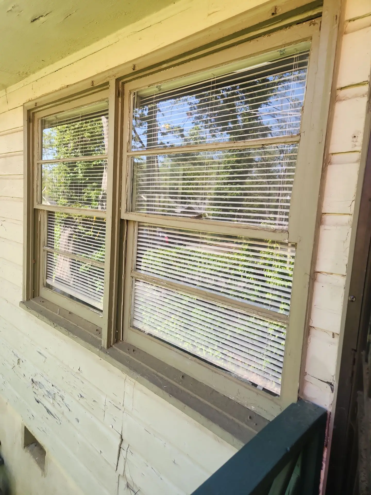 Close-up of an old wood-framed, double-hung window showing deteriorated sash and drafty mechanisms.